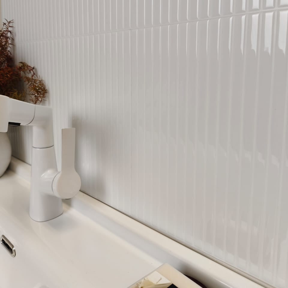 White bathroom sink with faucet against a tiled wall
