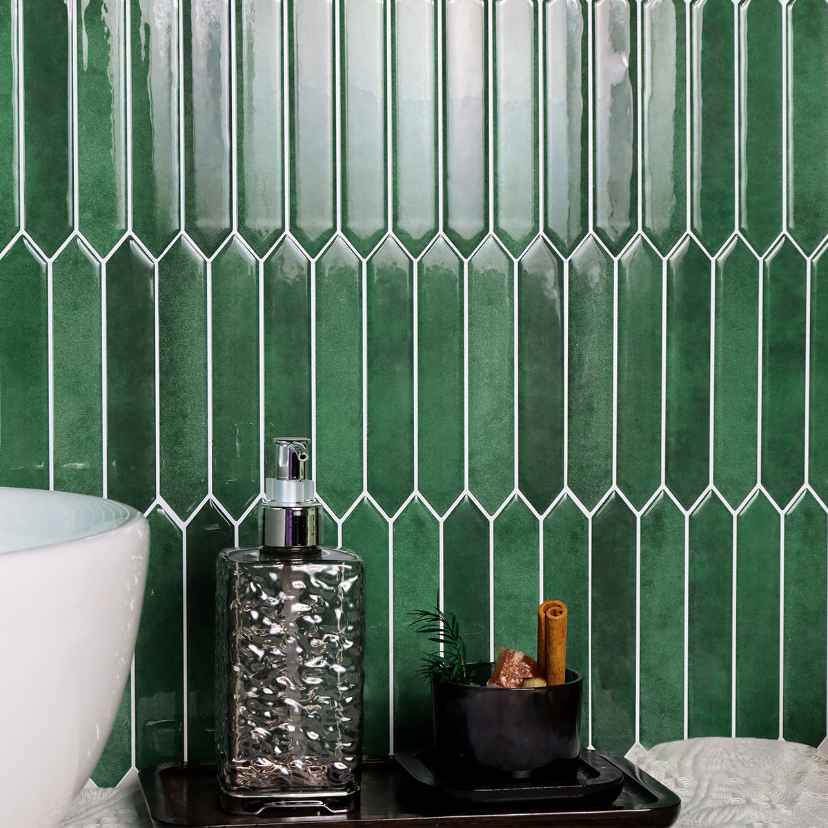 Bathroom setting with green picket tiled wall, white sink, and decorative items on a tray.