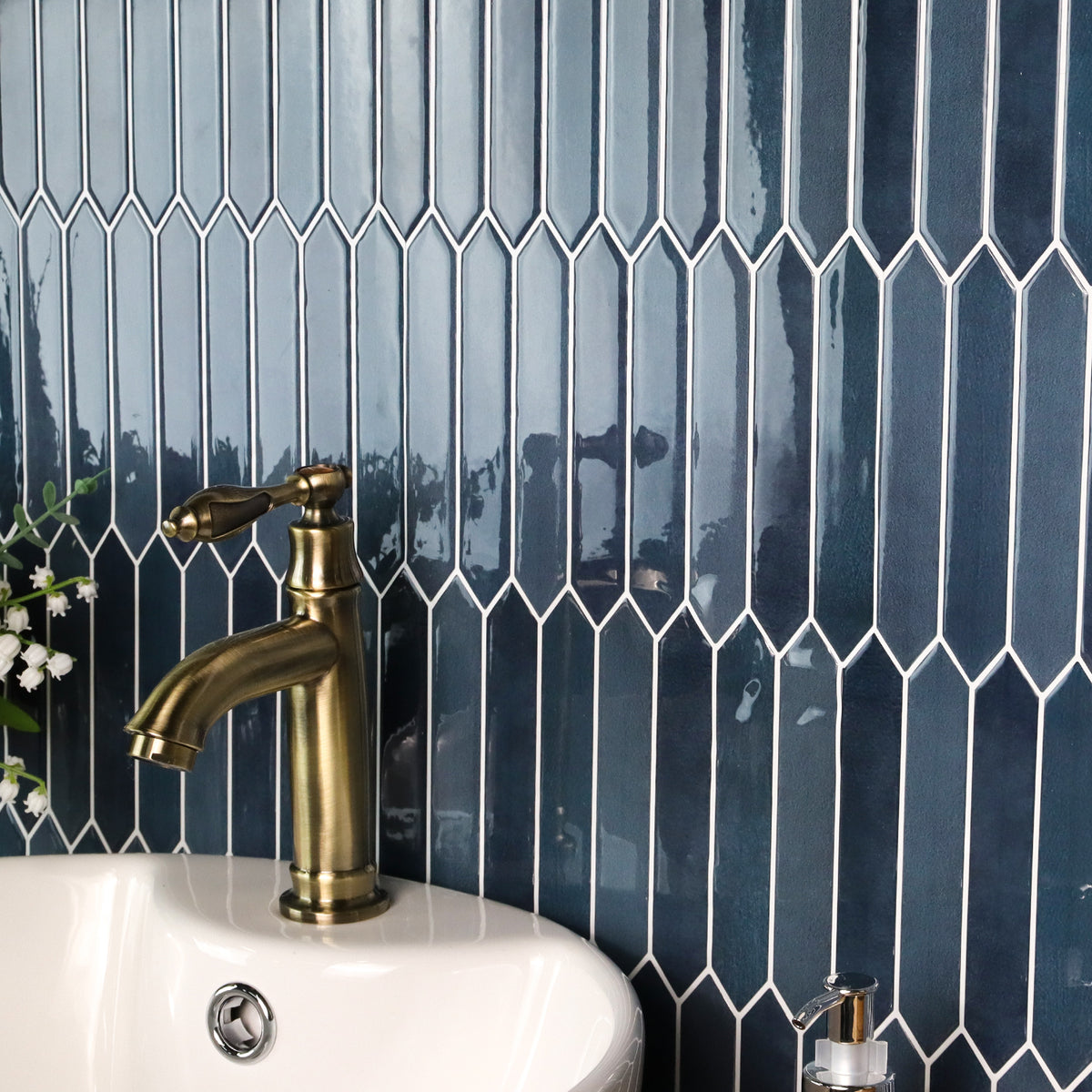 Bathroom sink with gold faucet against a blue tiled wall
