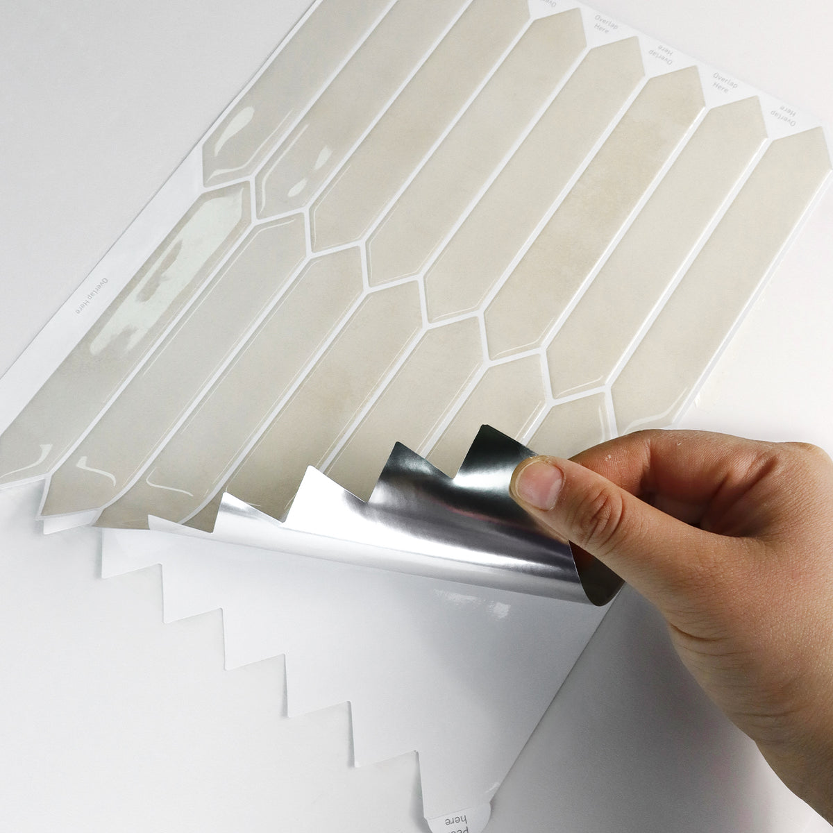 Hand applying a decorative sandy picket tile sheet with geometric pattern to a surface.