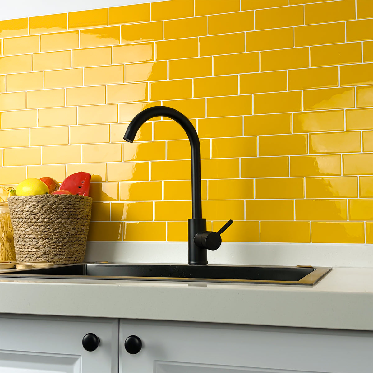 Kitchen sink with black faucet against a yellow tiled wall