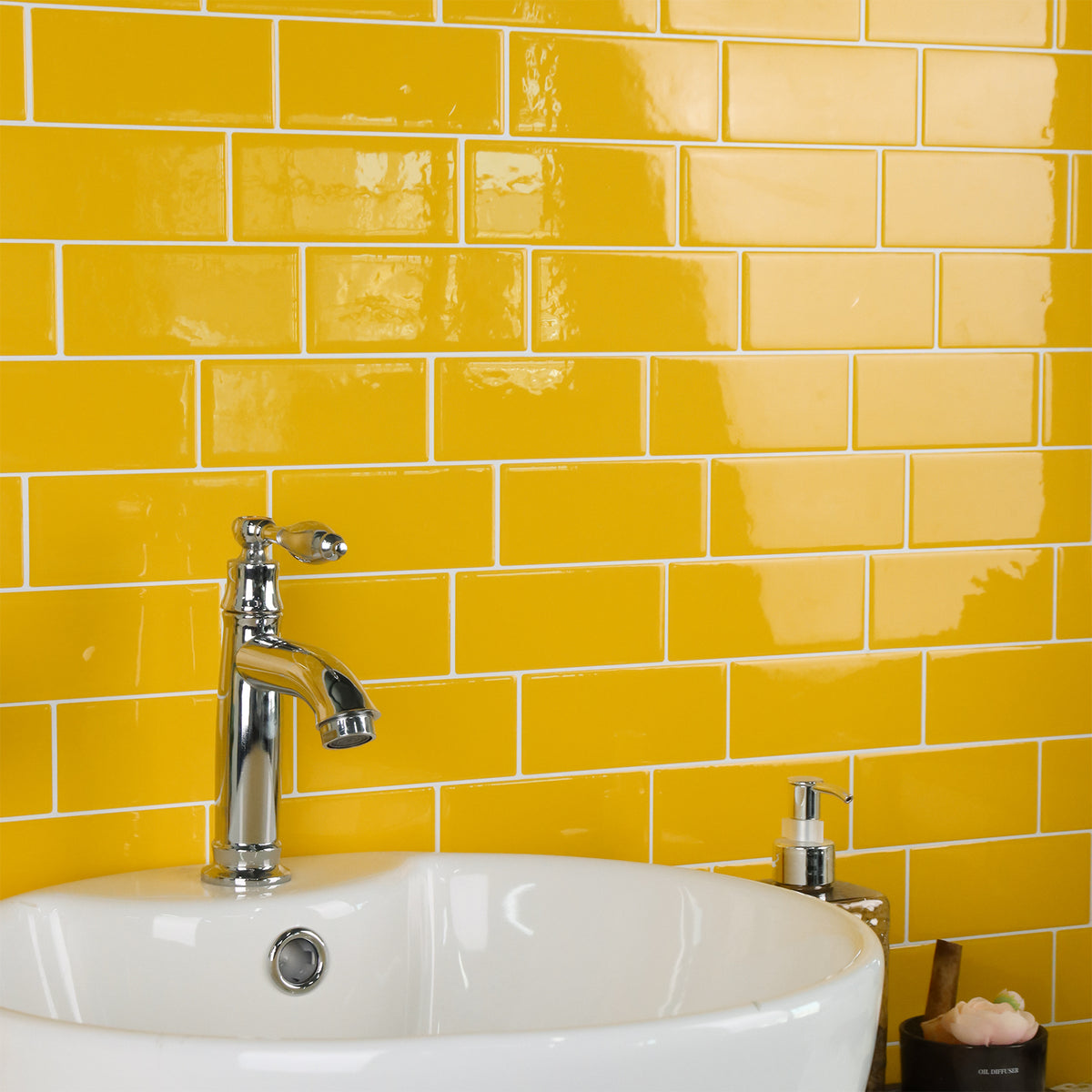 White sink with silver faucet against a yellow tiled wall