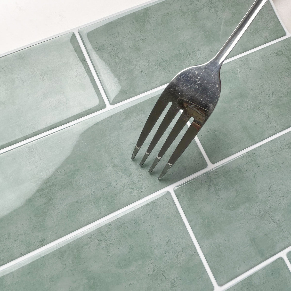 Silver fork on a green tiled surface showing how scratch resistant they are