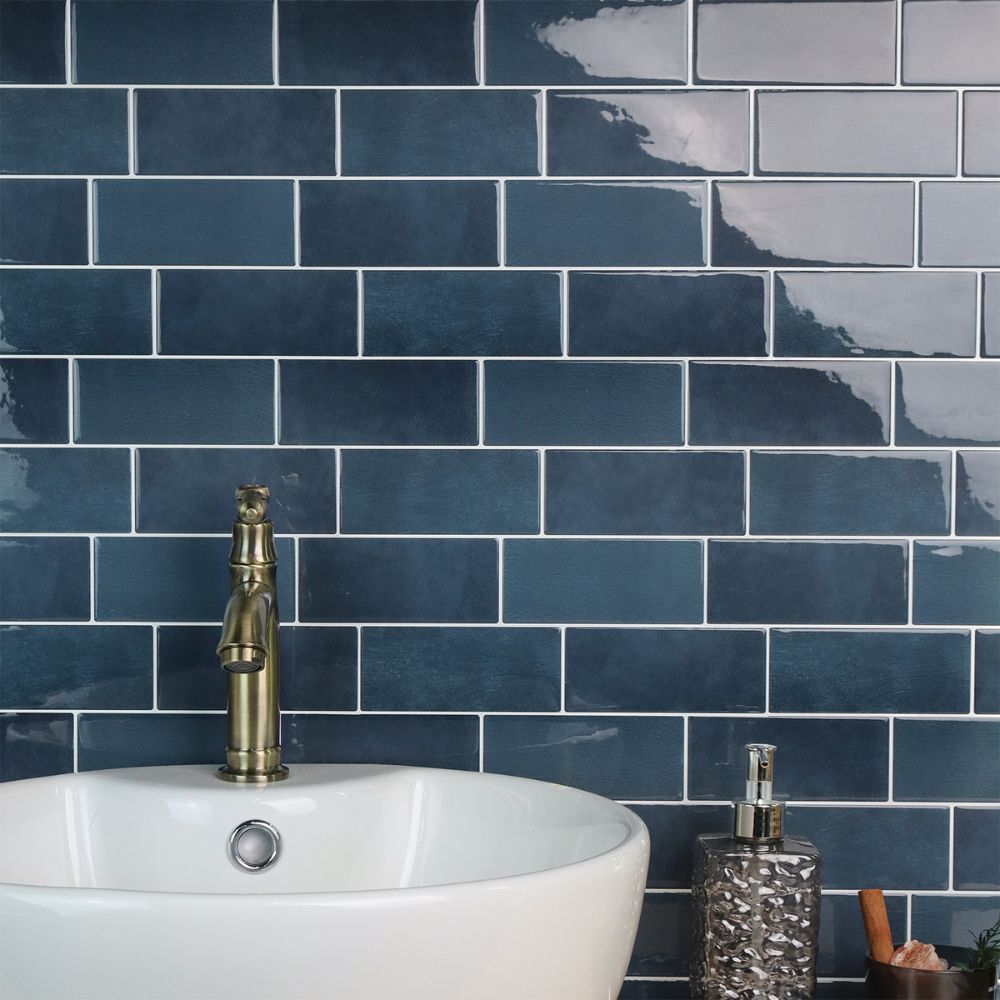 Bathroom with blue tiled wall, white sink, and gold faucet.