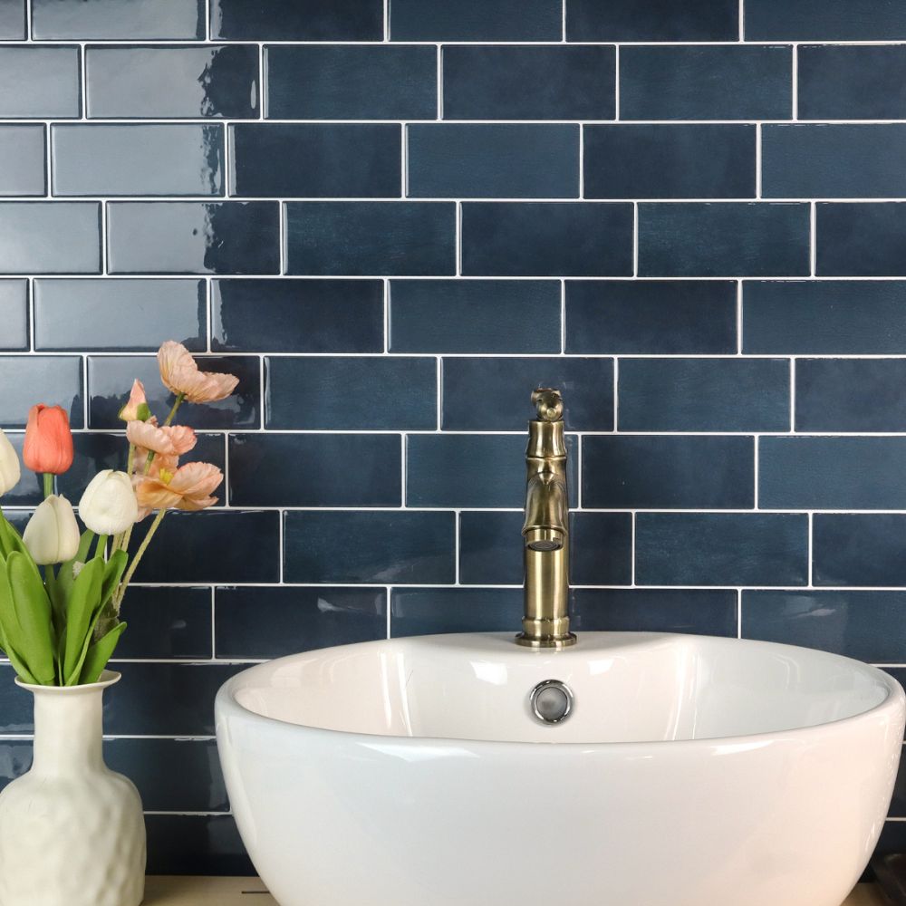 White sink with brass faucet against a blue tiled wall