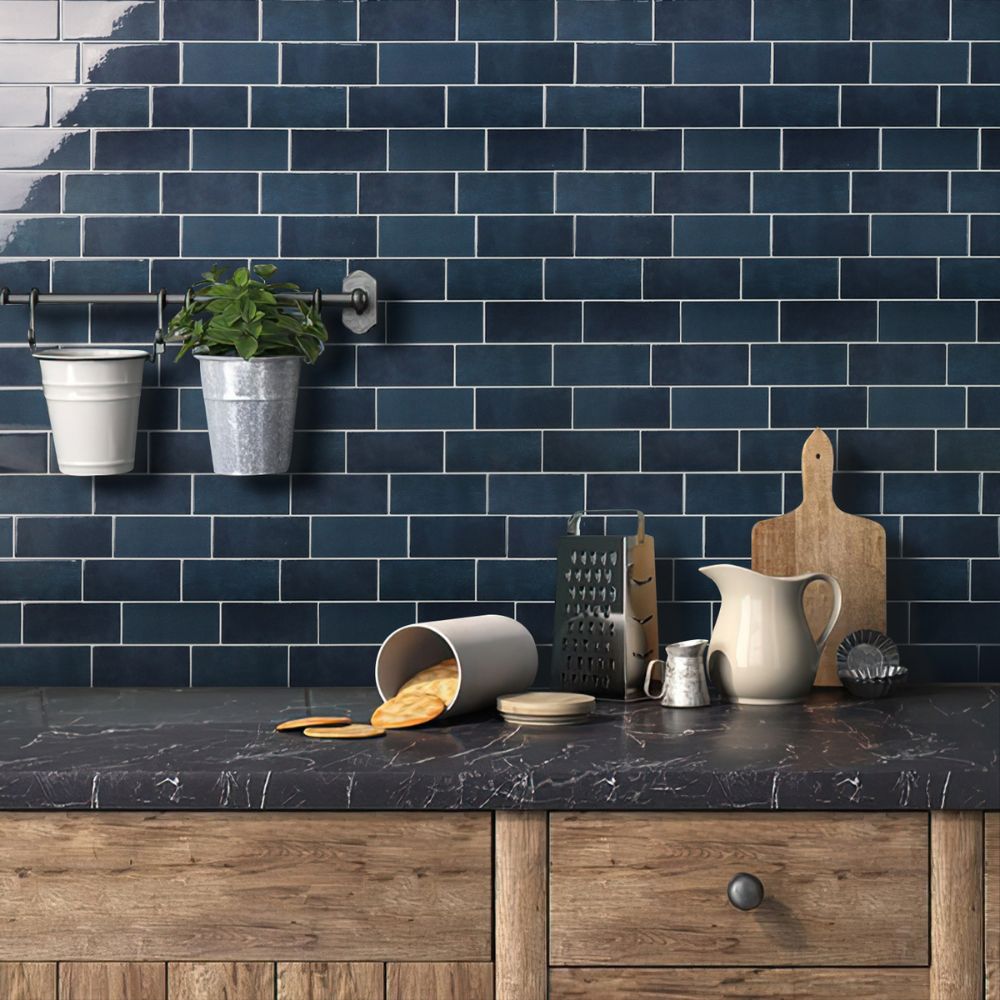 Kitchen counter with dark blue tiled wall and various kitchen items.