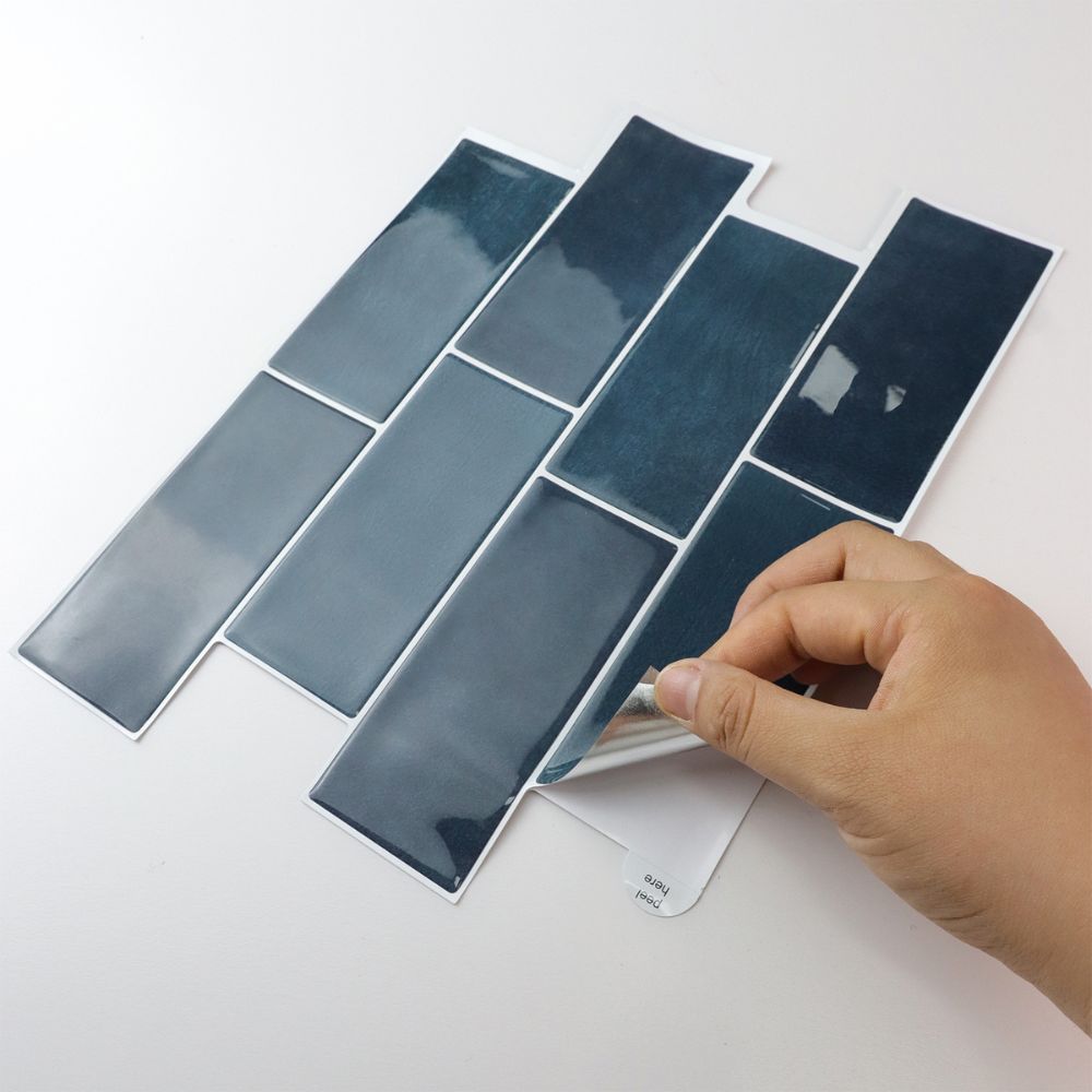Blue peel and stick tiles on a white surface with a hand holding one tile.