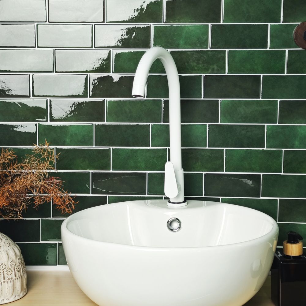 White sink with a white faucet against a green tiled wall
