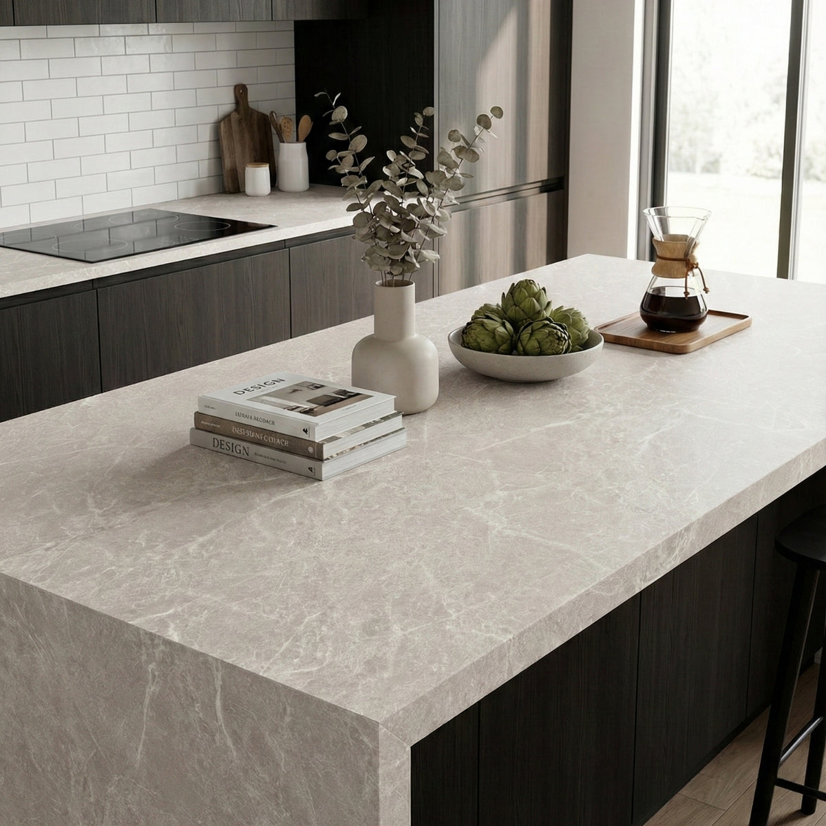 Modern kitchen with a marble vinyl wrapped countertop, books, wine, and a bowl of fruit.
