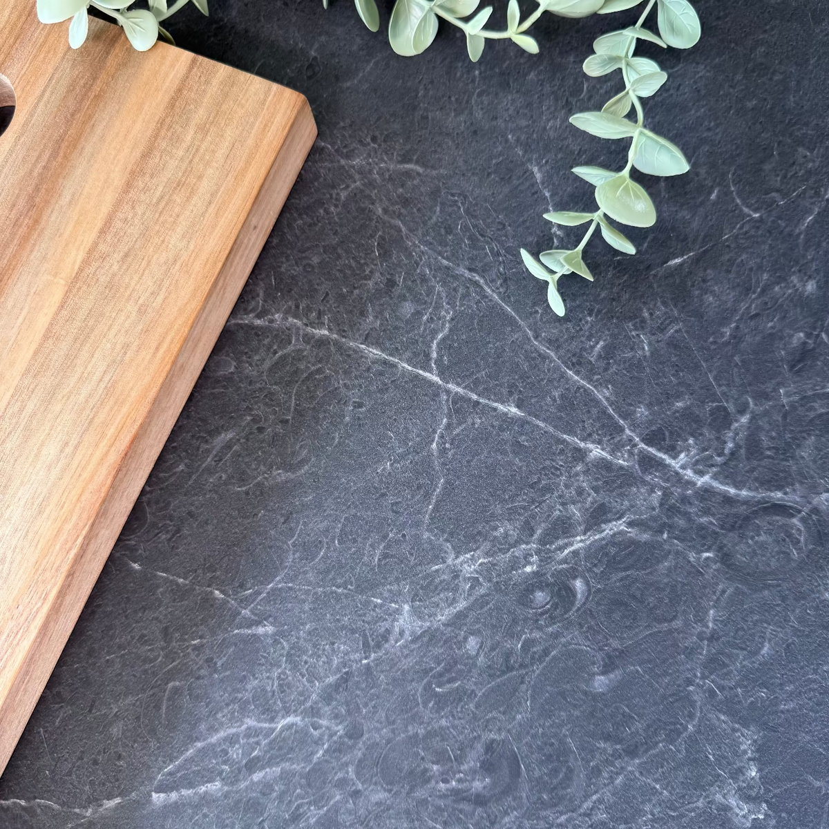 Dark stone architectural grade adhesive vinyl with a wooden cutting board and green leaves