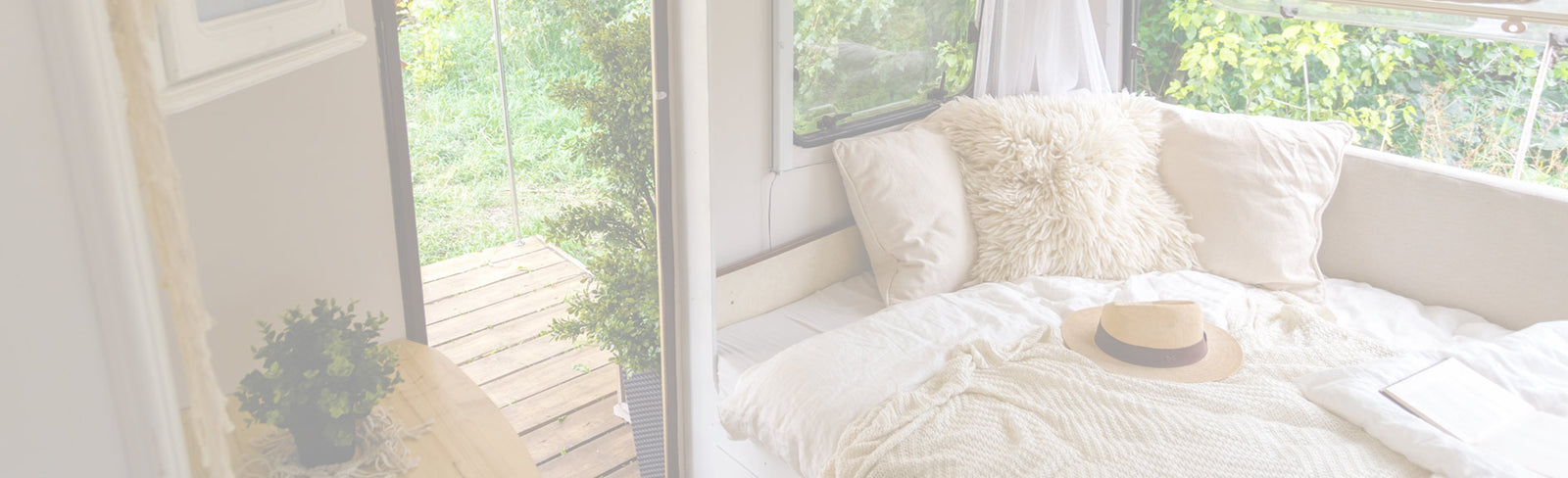 Bright sunroom with white window seat and white cushions and greenery outside the window