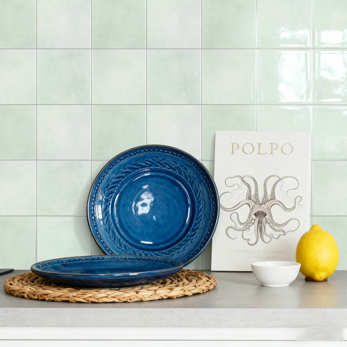 Blue ceramic plates on a kitchen counter with a 'Polpo' poster in the background.