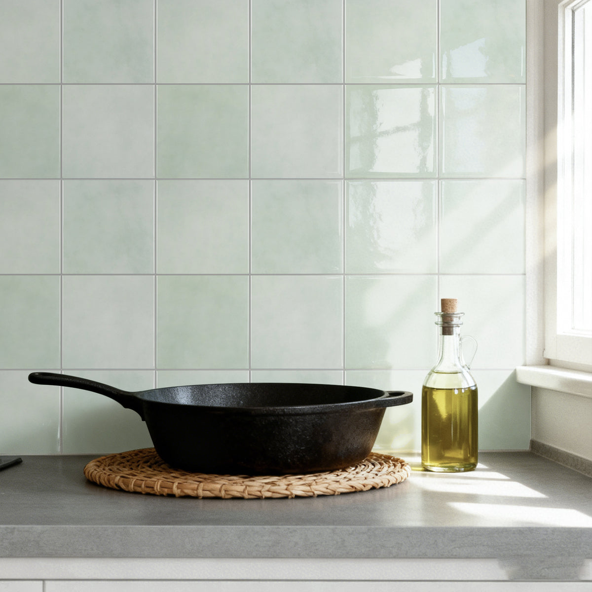 Black cast iron skillet on a kitchen counter with a bottle of oil against a tiled wall.