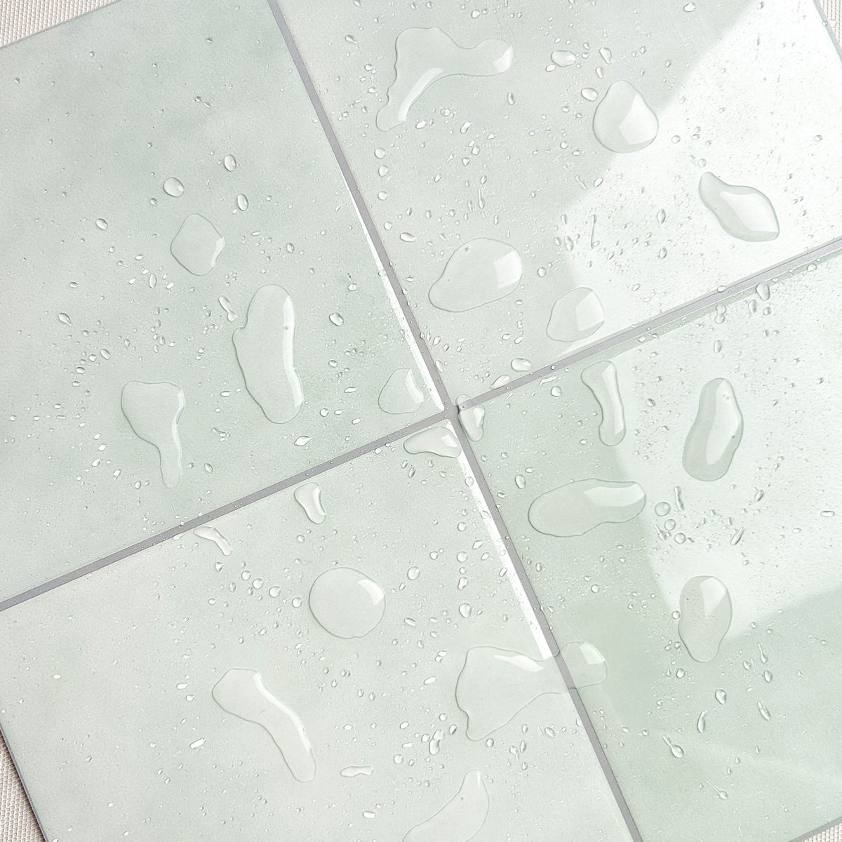 Close-up of light green tiles with water droplets on a textured surface