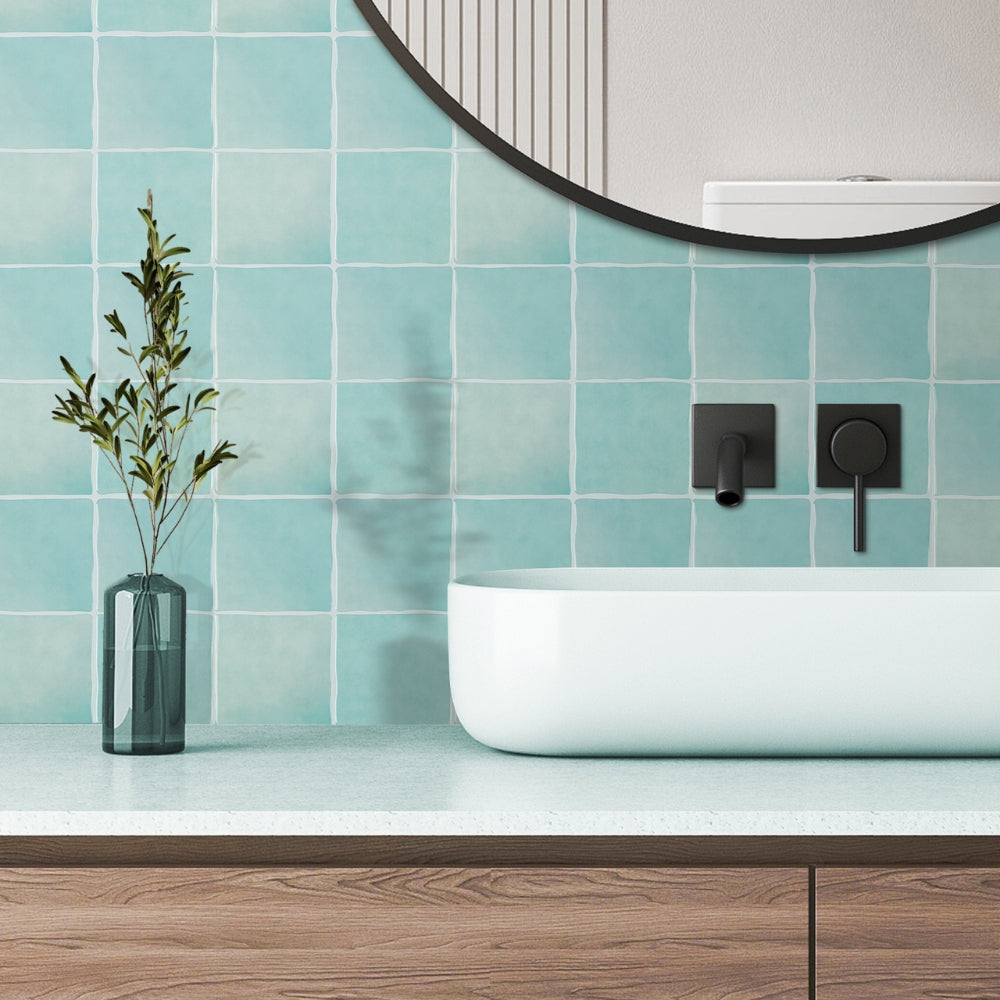 Modern bathroom with blue tiled wall, white sink, and wooden vanity.