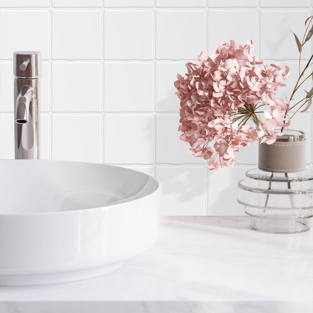 Bathroom with white tiles, a sink, and a vase with pink flowers.
