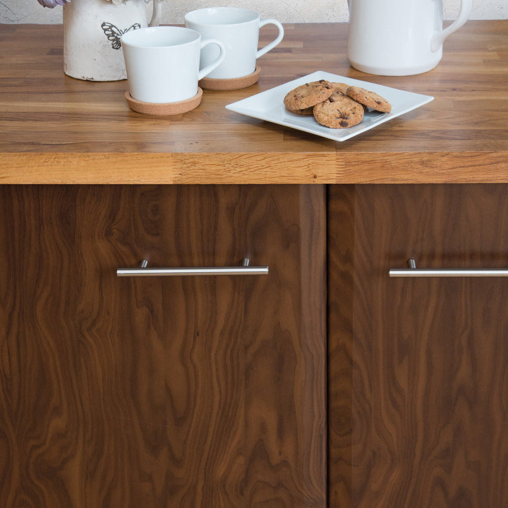 Wooden cabinet with ceramic items including mugs, a teapot, and cookies on a wooden surface.