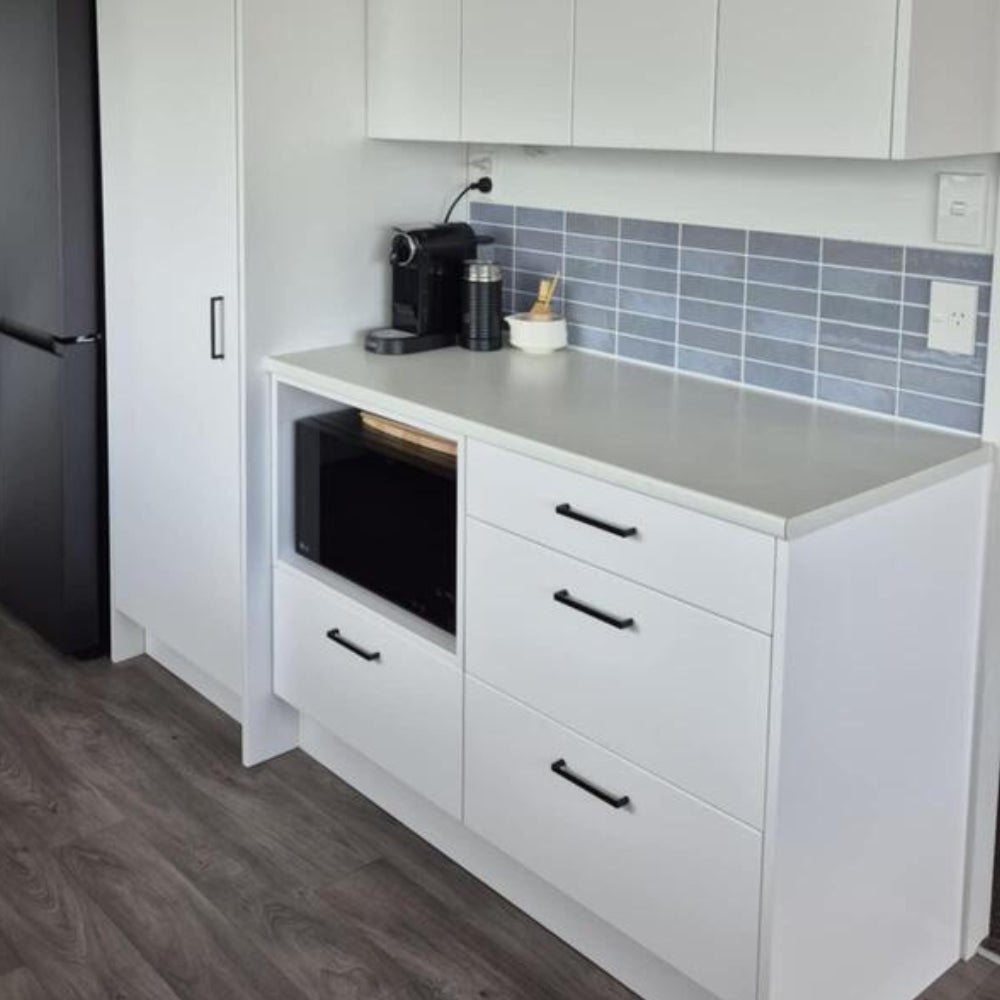 Modern kitchen with white cabinets, gray countertop, and black appliances.
