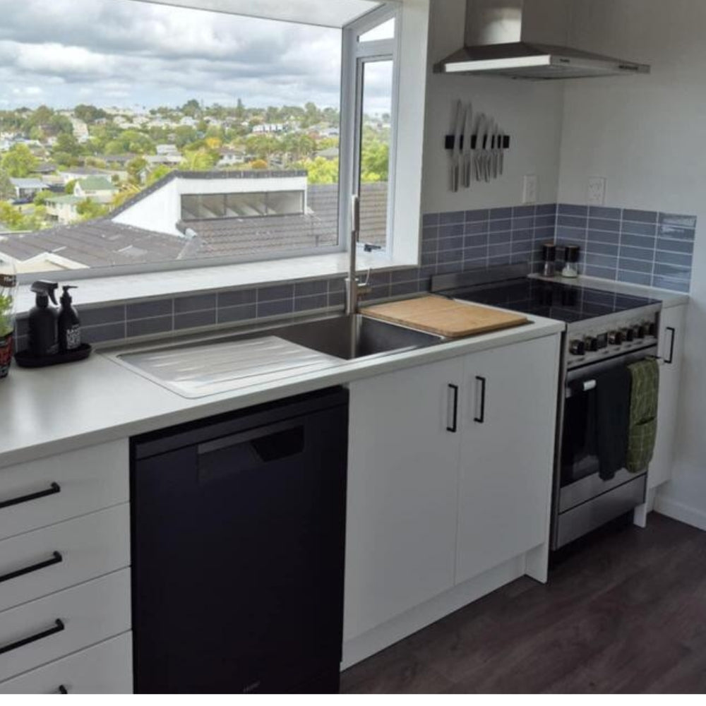 Modern kitchen with white cabinets, black appliances, and a view of a residential area.
