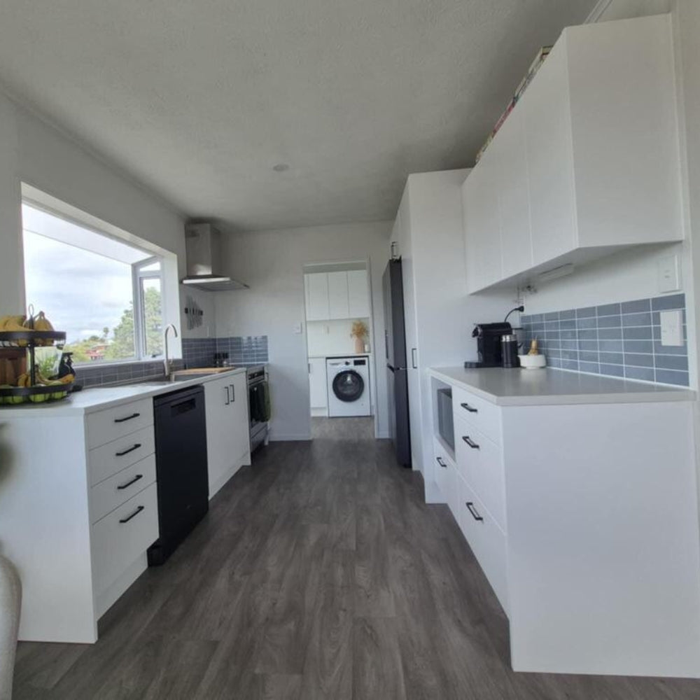 Modern kitchen with white cabinets, gray flooring, and blue backsplash.