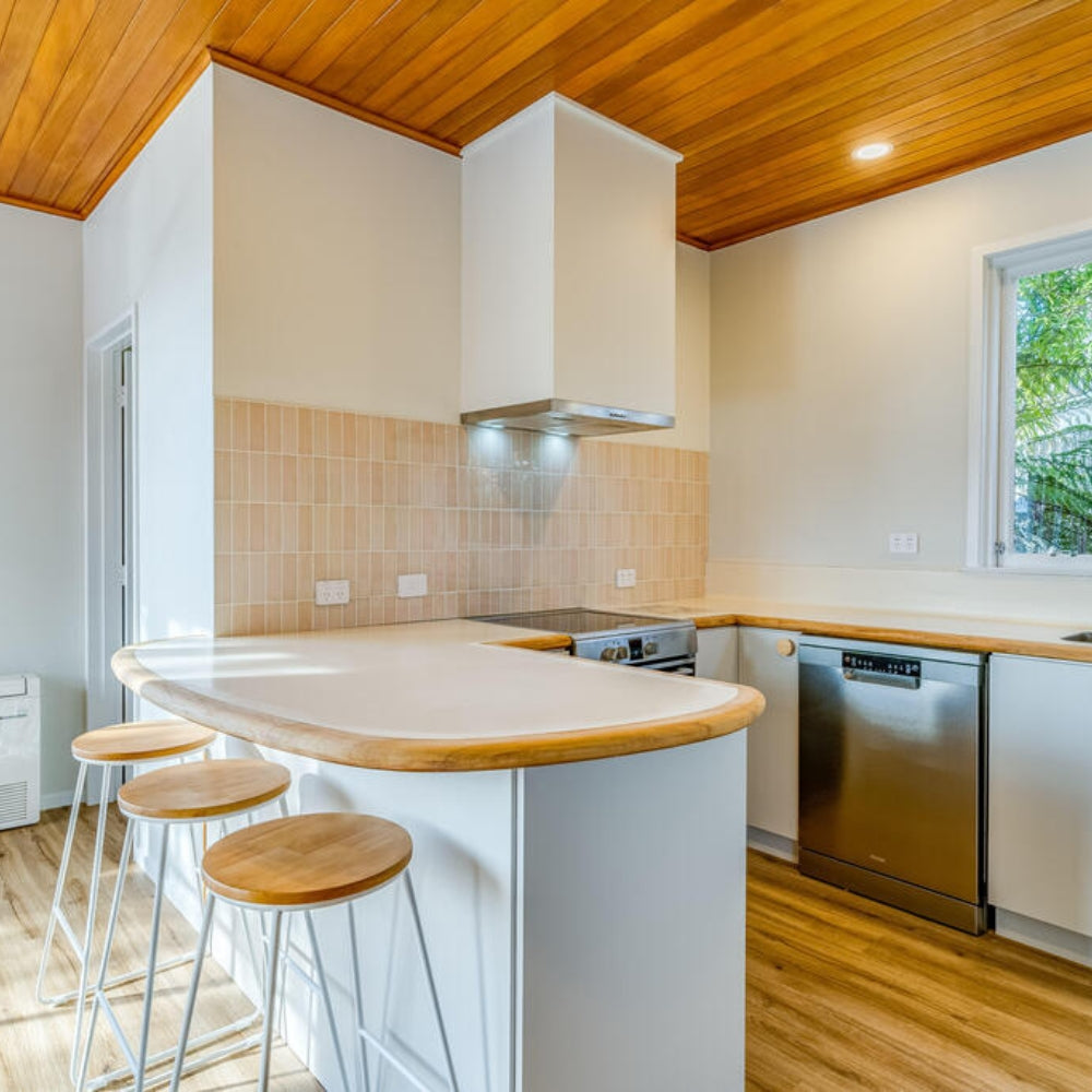 Modern kitchen with wooden ceiling, white cabinets, and a breakfast bar.