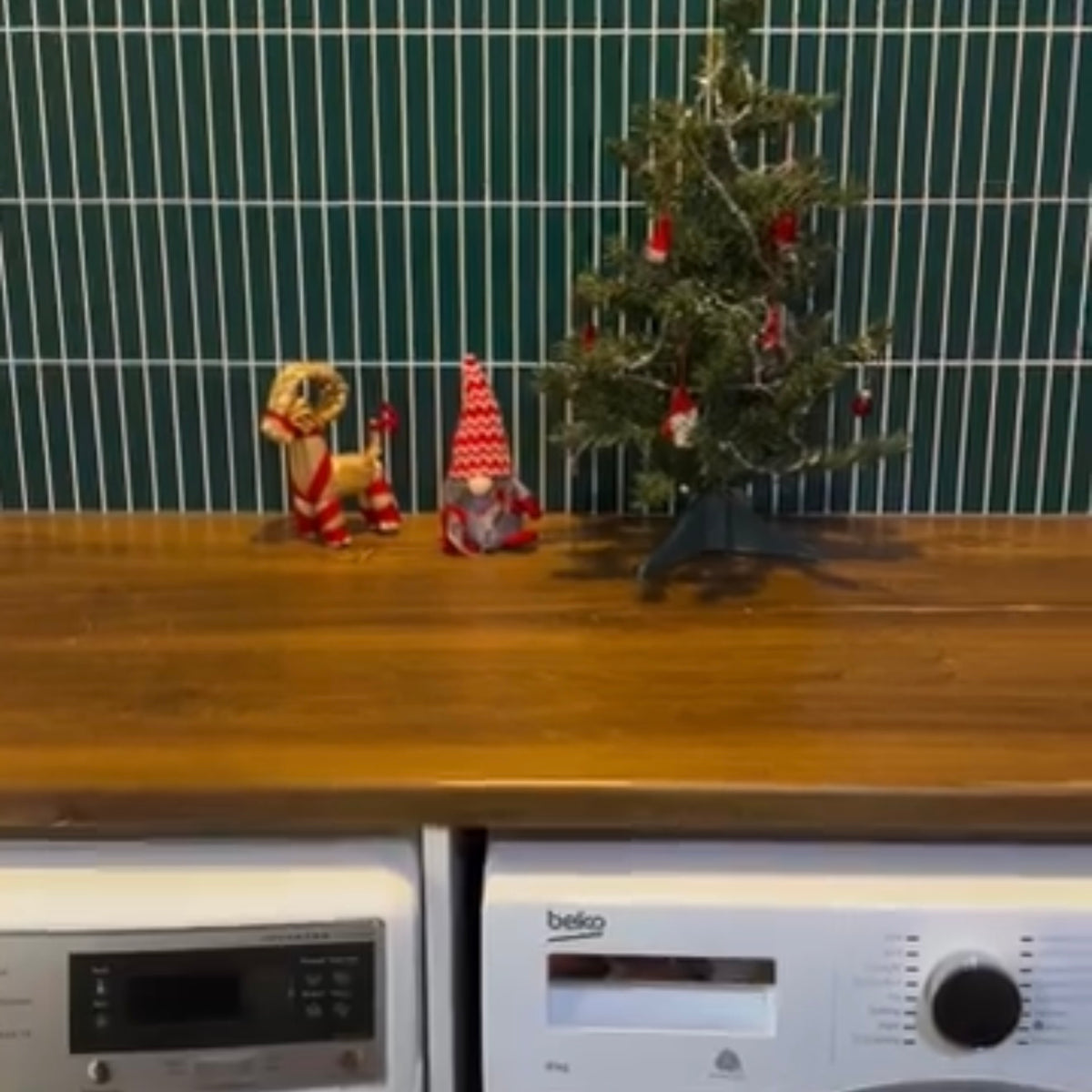 Small Christmas tree with decorations on a wooden laundry bench top