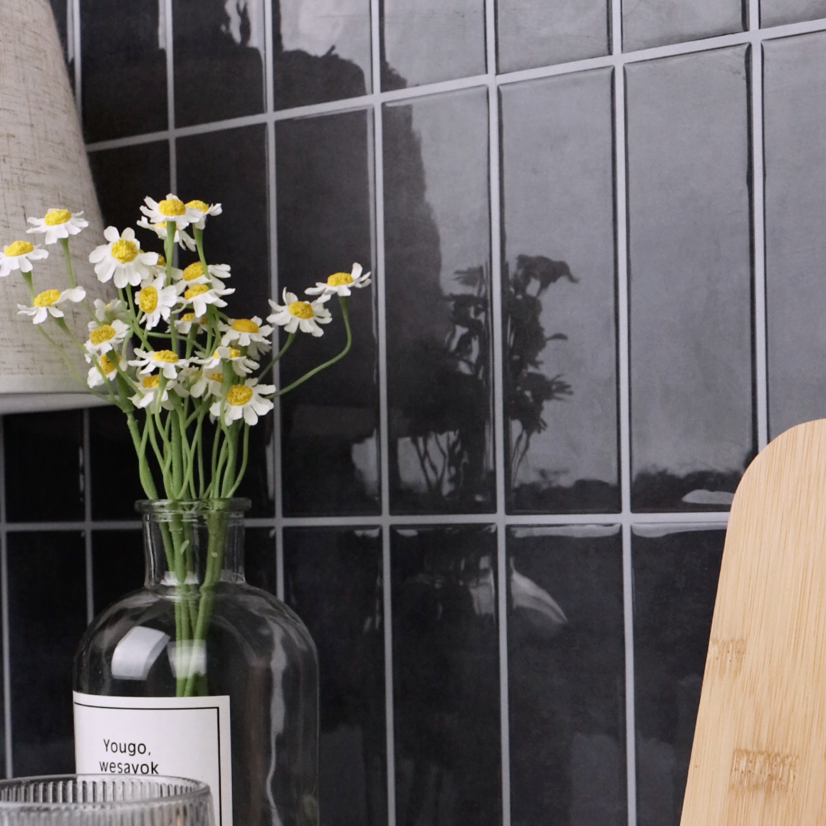 Vase with flowers against a dark grey tiled wall