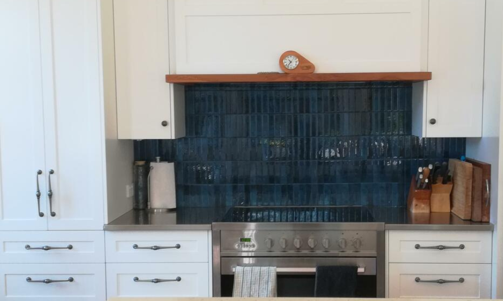 Kitchen with blue self-adhesive tiled backsplash and white cabinets