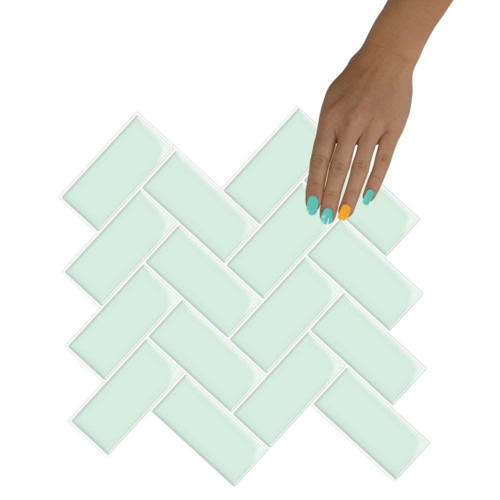 Light green tiles arranged in a herringbone pattern with a hand touching one of them.