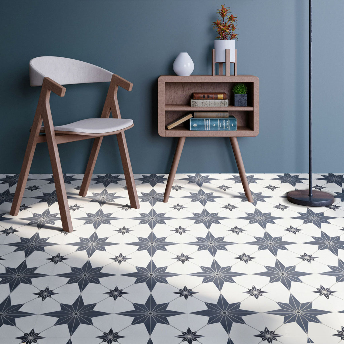 A styled interior scene showing a white floor with a repeating blue geometric star pattern, a wooden chair with a light seat, a small wooden side table, and a blue wall.