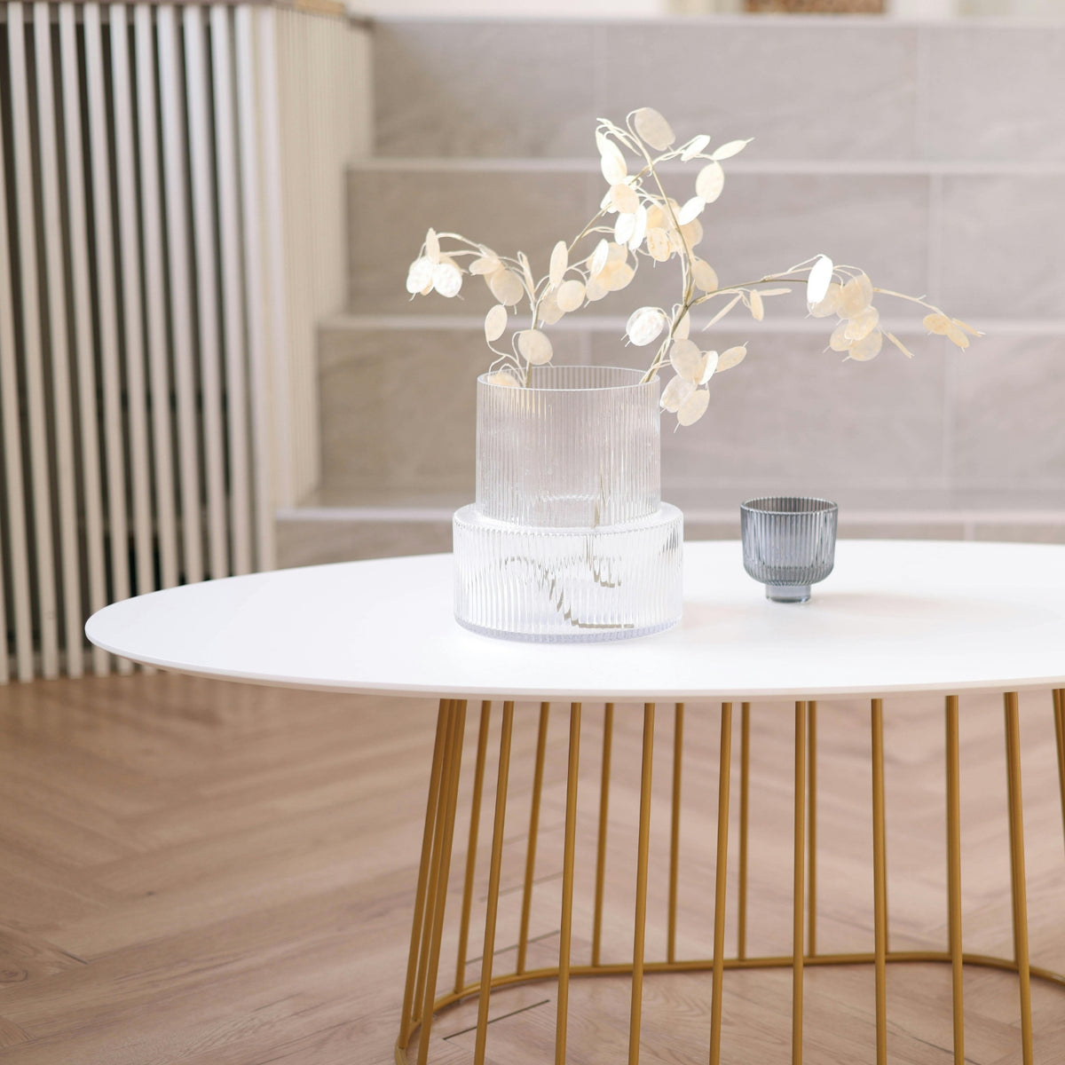 Modern coffee table with a vase of white flowers and a small gray cup in a minimalistic room.