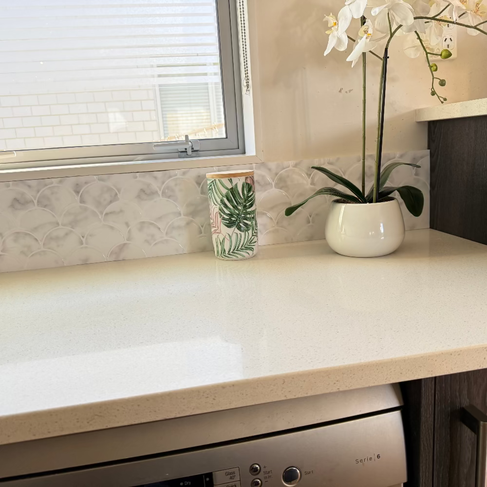 Kitchen countertop with a vase of flowers and a window in the background